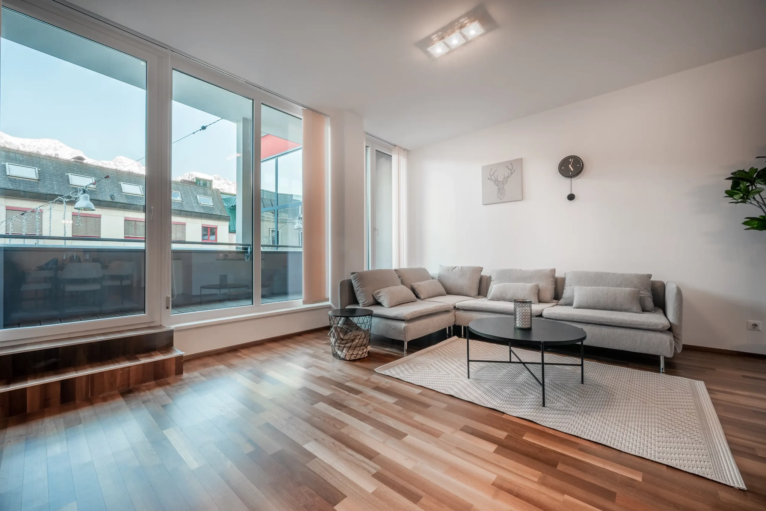 Helles Wohnzimmer im CityFLAT 38 Appartement by globboard in Schladming-Dachstein, mit moderner Couch, großem Fenster und Balkonzugang.