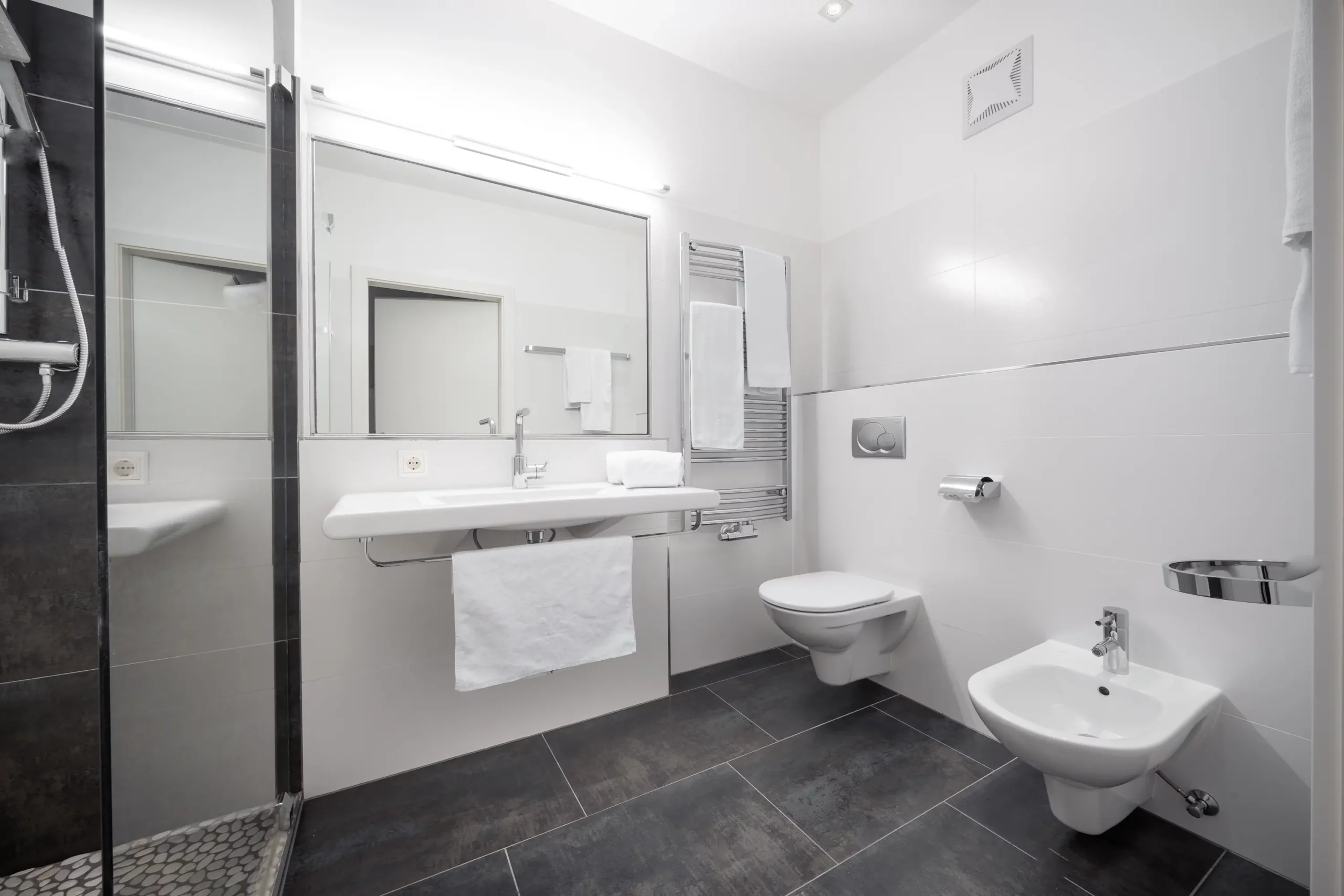 Hochwertig ausgestattetes Badezimmer im CityFLAT 38 Appartement by globboard in Schladming-Dachstein, mit ebenerdiger Dusche, Waschbecken, Bidet, wandhängender Toilette und Handtuchheizung – ideal für Komfort nach einem Tag beim Skifahren oder Wandern in der Steiermark.