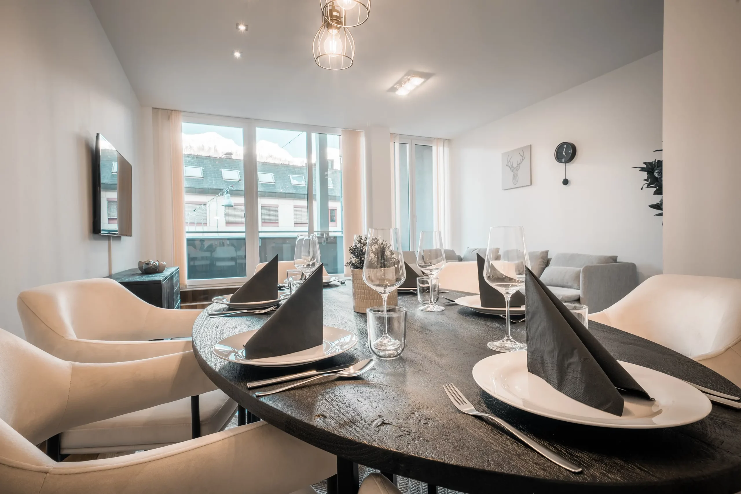 Stilvoll gedeckter Esstisch im CityFLAT 38 Appartement by globboard in Schladming-Dachstein, mit modernen Stühlen, großem Fenster und Blick auf den Wohnbereich.